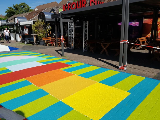 Bunte bemalter Weg im Kaufhof vor Bars mit Tischen und Bänken.