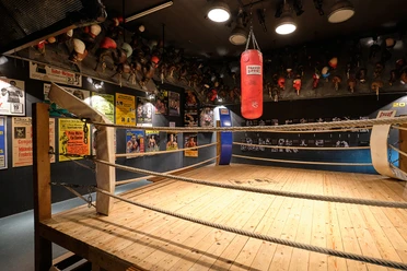 Deutsches Sport & Olympia Museum - Ausstellungsraum Boxring mit Sandsack, Boxhandschuhen und historischen Plakaten im Sportmuseum Köln