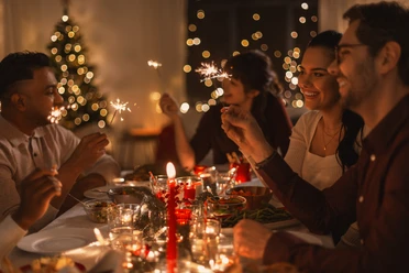 happy friends with sparklers at christmas dinner
