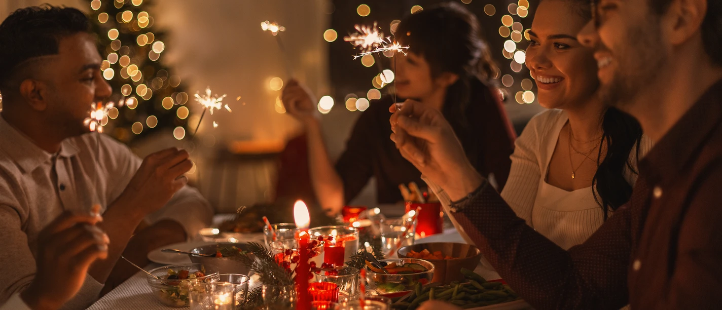 happy friends with sparklers at christmas dinner