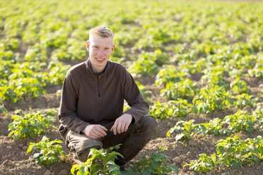 Lucas Mohme kniet im Gemüsefeld