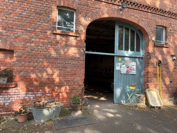 Rotes Ziegelsteinhaus mit großer Eingangtür. Darüber ein Werbeschild mit der Aufschrift: Tims Landbau.