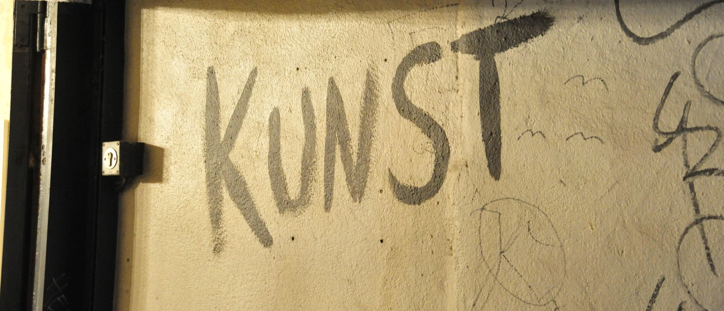 Graffiti mit dem Wort Kunst auf einer sonnenbeschienenen Wand.