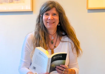 Eine Frau mit braunen langen Haaren ist dabei, ein Buch zu lesen..