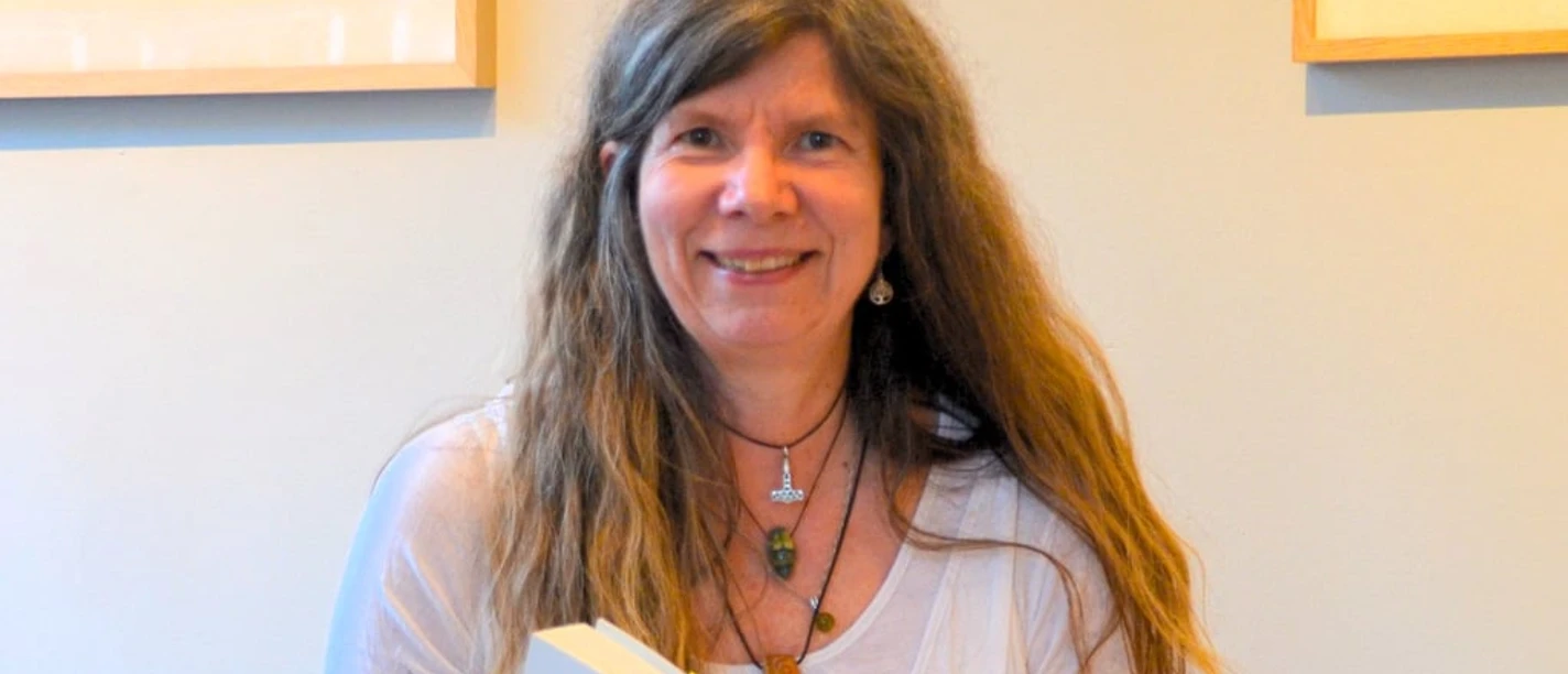 Eine Frau mit braunen langen Haaren ist dabei, ein Buch zu lesen..