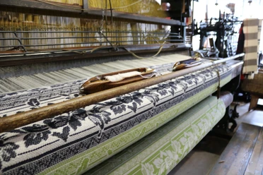 Tuchmacher Museum Bramsche Webstuhl mit floralen Mustern in Blau und Grün, Textilherstellung im traditionellen Stil.