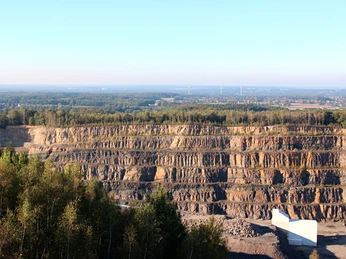 Piesberg Steinbruch mit gestuften Felswänden im Vordergrund, dahinter weitläufige Waldlandschaft.Quarry with stepped rock faces in the foreground, extensive forest landscape behind.Stenbrud med aftrappede klippevægge i forgrunden, stort skovlandskab bagved.Steengroeve met getrapte rotswanden op de voorgrond, uitgestrekt boslandschap erachter.