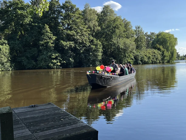 Festlich geschmücktes Boot mit Gästen auf der Hamme bei Melchers Hütte.