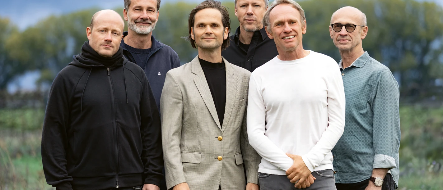 Bandfoto von Keimzeit: sechs Männer stehen im Freien vor unscharfer Naturkulisse.