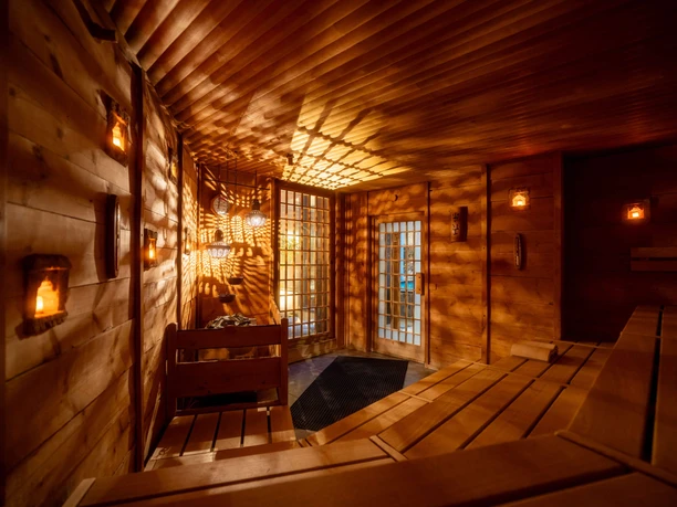 Neptunbad - Candle Sauna Candlelit sauna at Neptunbad with wooden loungers, warm lighting, and decorative lanterns