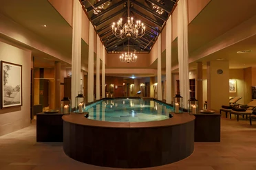 Evening atmosphere at the Claudius Therme spa, featuring a pool, candles, and chandeliers