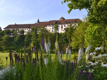 Historisches Schloss umgeben von üppigen Gärten, sommerliche Blütenpracht im Vordergrund.Historic castle surrounded by lush gardens, summer flowers in the foreground.Historisk slot omgivet af frodige haver, sommerblomster i forgrunden.Historisch kasteel omringd door weelderige tuinen, zomerbloesems op de voorgrond.