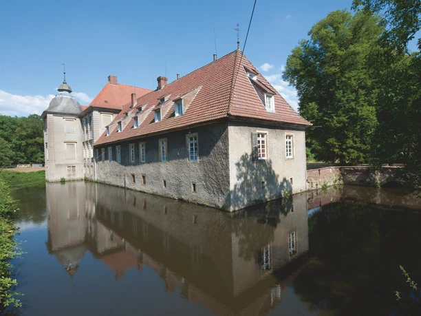 Radeln auf der Hügeltour Omgracht kasteel met vakwerk, omgeven door een slotgracht, tegen een blauwe lucht.