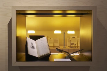 Aufgeschlagenes Buch in beleuchteter Museumsvitrine