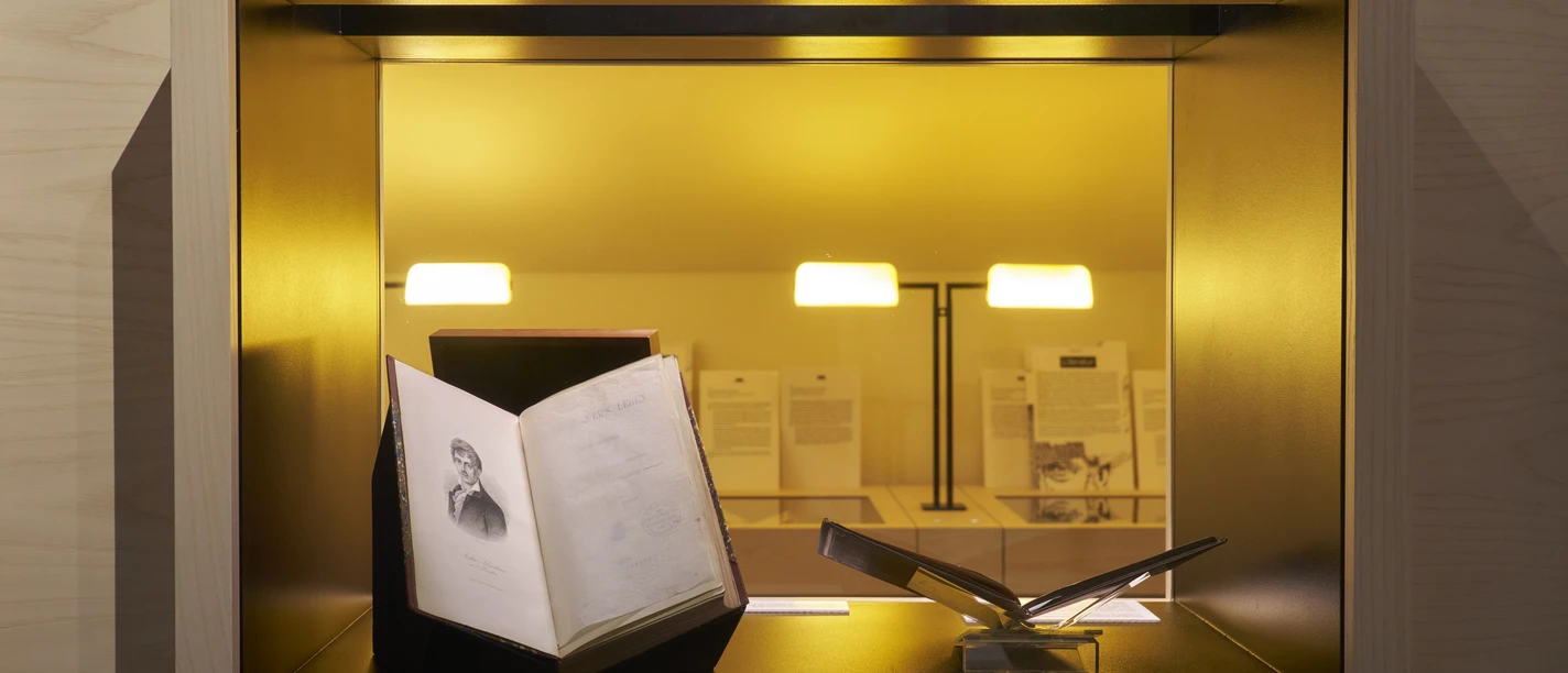 Aufgeschlagenes Buch in beleuchteter Museumsvitrine