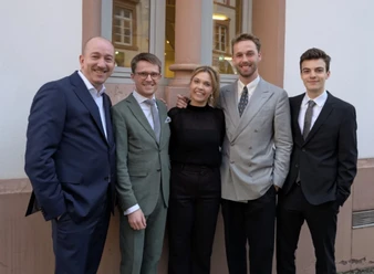 Chris Hopkins and the Young Lions posieren in formeller Kleidung vor einem Gebäude.