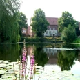 Fahrradtour "Rund um Belm" Historische Backsteingebäude spiegeln sich in einem von Seerosen bedeckten Teich.