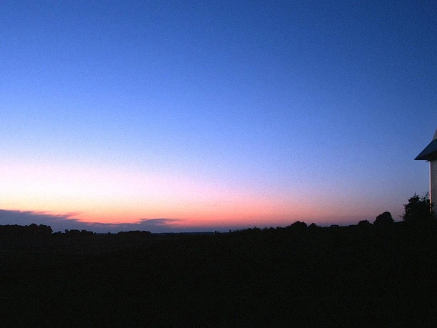 Radeln auf dem M6 - Rund um Oldendorf / Gesmold Ein einsames Haus steht vor der Silhouette eines klaren Sonnenuntergangs am Horizont.