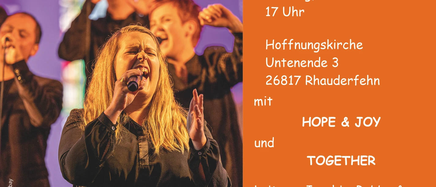 Gospelchor auf der Bühne, rechts orangefarbene Infotafel zum Konzert in Rhauderfehn.