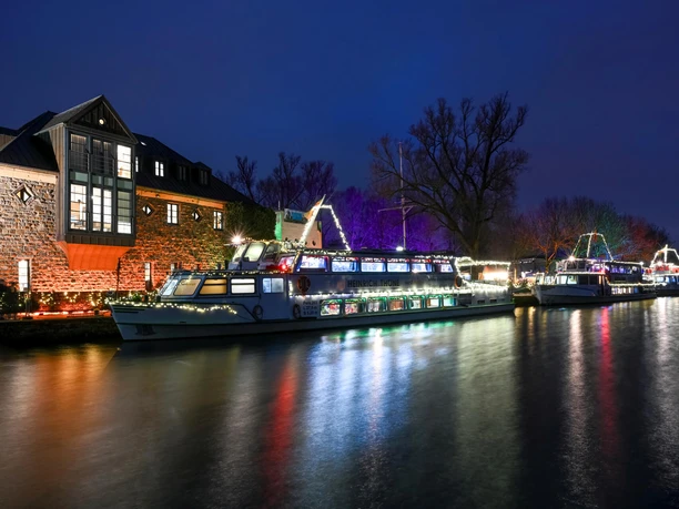 Schiffsweihnacht, Mülheim an der Ruhr Festlich beleuchtete Schiffe liegen abends an der Ruhr vor der Schleuseninsel.