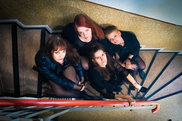 Vier Frauen in dunkler Kleidung auf einer Treppe, Draufsicht.