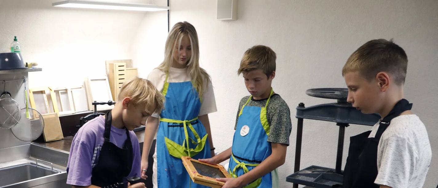 Kinder schöpfen Papier in Werkstatt des Museums