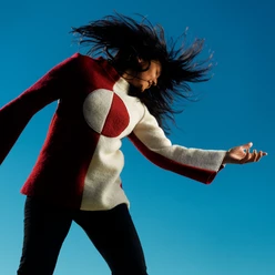 Person in rot‑weißem Oberteil vor blauem Hintergrund