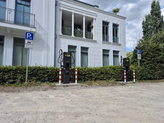 Zwei EWE-Go-Ladesäulen vor weißem Gebäude mit ausgewiesenen Parkplätzen.