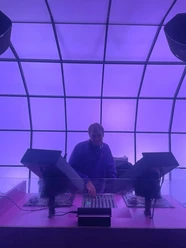 DJ at mixing desk under purple lit ceiling