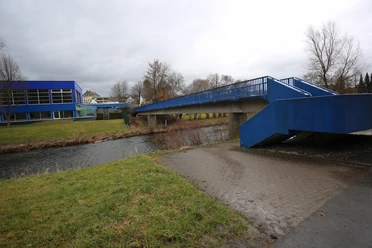 Blaue Fußgängerbrücke vomn Parkplatz in der Arnsberger Straße zum Freibad Meschede über die Ruhr bei bedecktem Himmel