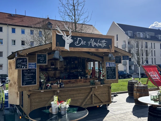 Holzstand „Die Almhütte“ mit Speisen und Getränken im Freien