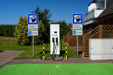 Eine E-Ladesäule vor einem Garten