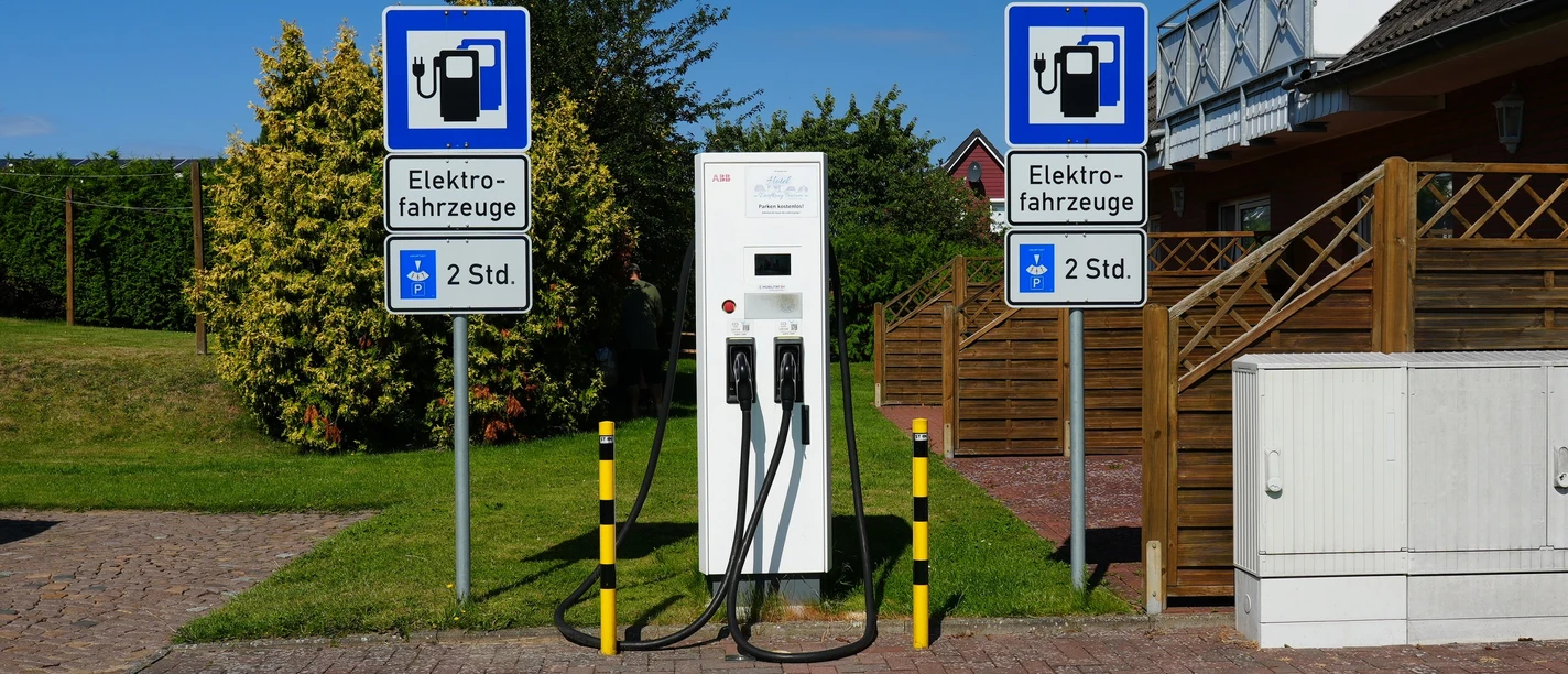 Eine E-Ladesäule vor einem Garten