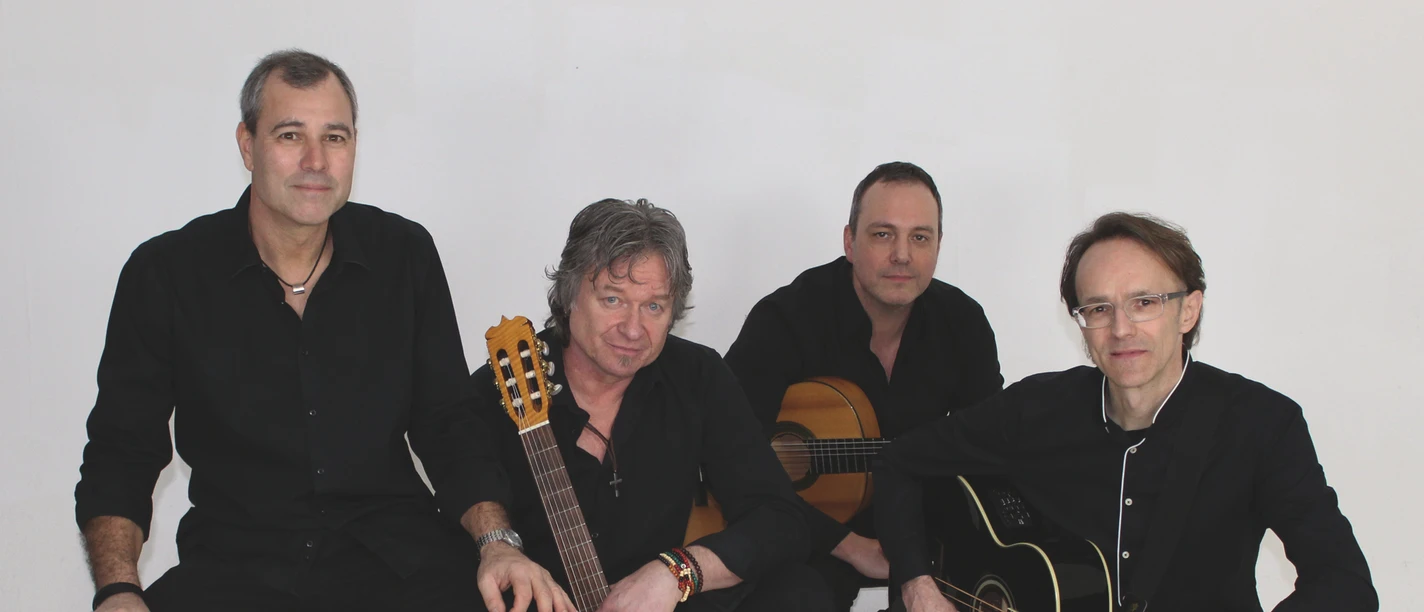 Vier Musiker in schwarzer Kleidung mit Gitarren und Cajón.