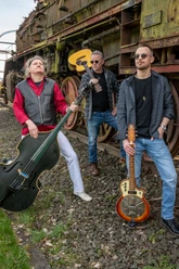 261205_TravelinBlues_KULTURSCHMIEDE_Kallmünz_(c)_Wolfgang_Weber.jpg Drei Bluesmusiker mit Gitarren und Kontrabass vor einer rostigen Dampflok