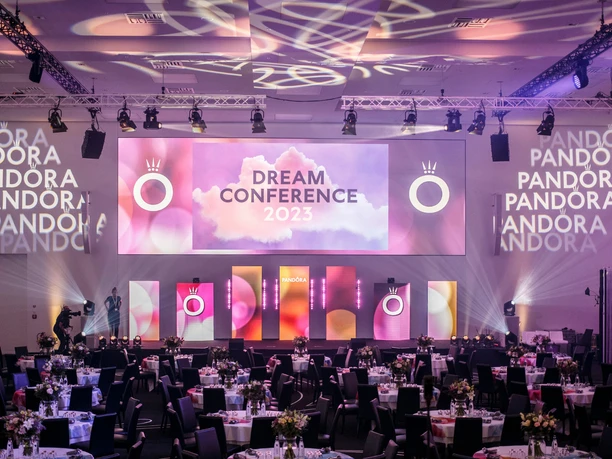 Festlich gedeckter Eventsaal mit Bühne und Projektion zur Pandora Dream Conference 2023