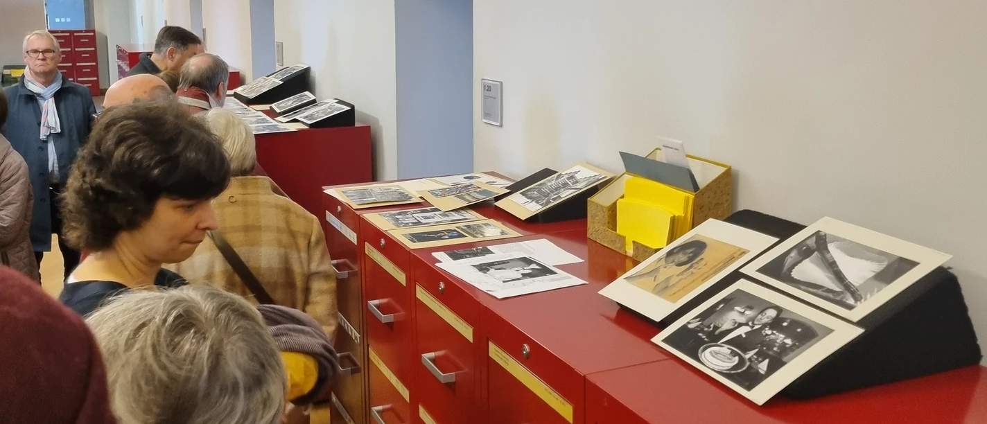 Besucher betrachten Fotos auf Archivschränken im Museum