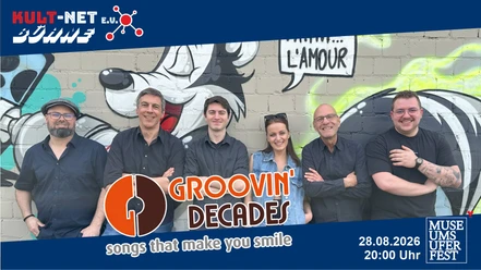 Sechs Bandmitglieder lächeln vor einer Wand mit Cartoon-Graffiti