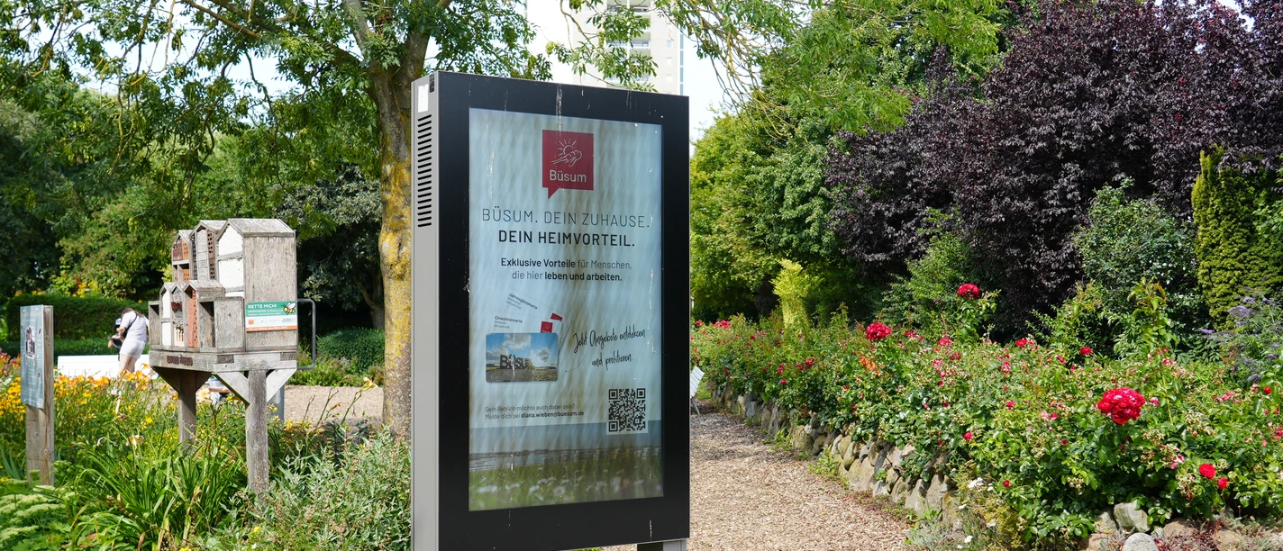 Eine Infotafel vor einer kleinen Grünfläche