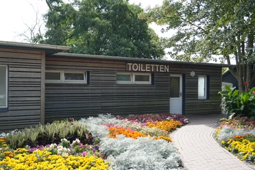 WC-Station hinter einem Blumenbeet