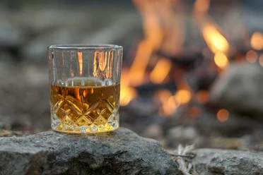Glas Whisky vor einem Feuer