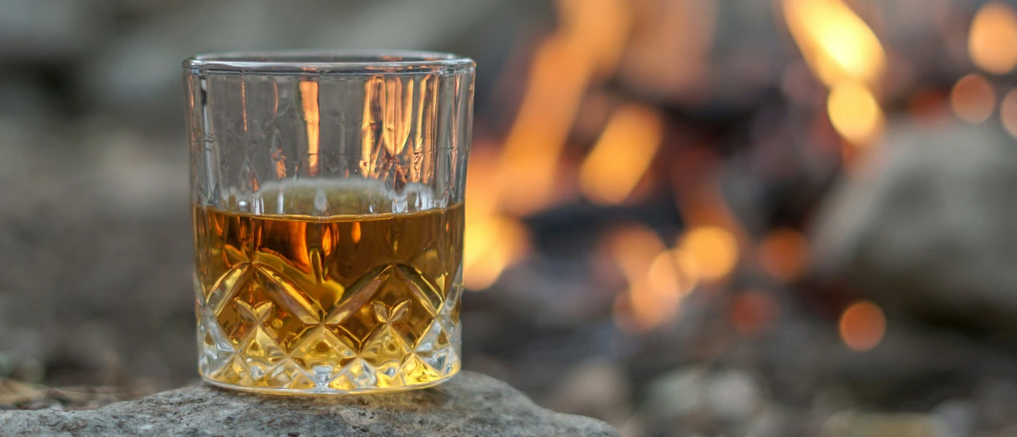 Glas Whisky vor einem Feuer