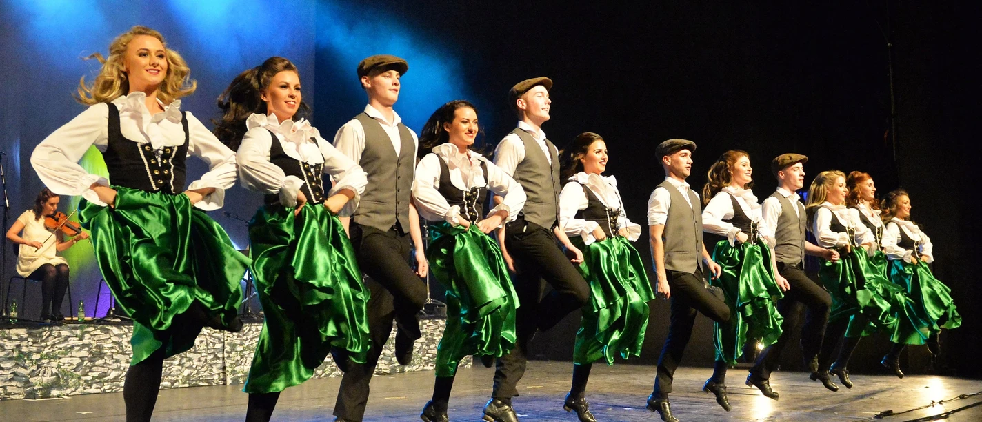 A - Danceperados_of_Ireland_-_an_authentic_show_of_Irish_music__song___dance_©_Gregor_Eisenhuth_live_A.jpg Irische Tanzgruppe in grünen Kostümen springt synchron auf der Bühne.