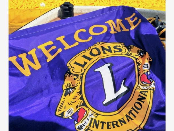 Ein Fluss voller gelber Gummienten mit einer "Welcome Lions International"-Flagge im Vordergrund.