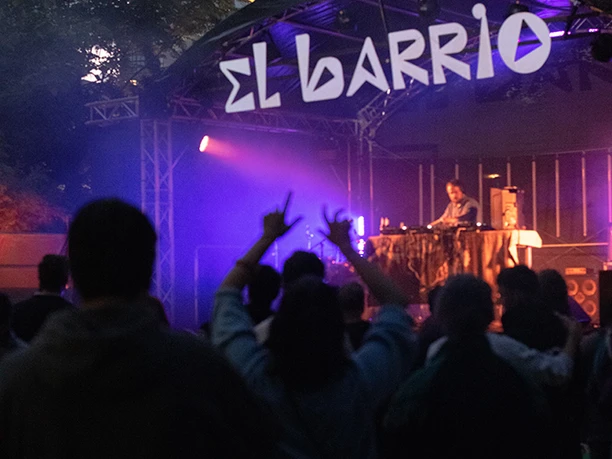 Konzertbühne "El Barrio" bei Nacht mit jubelndem Publikum.