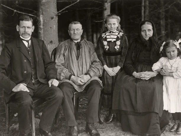 Black-and-white portrait of a family spanning three generations in the forest, 1912