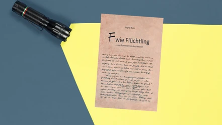 Im Lichtkegel einer Taschenlampe ist ein Brief mit der Überschrift zu sehen ""F wie Flüchtling"