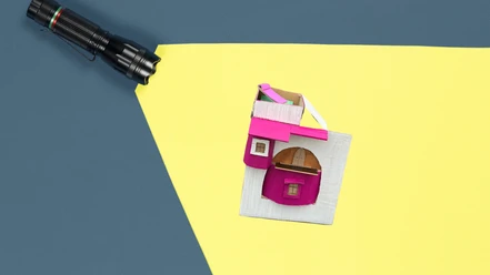 Im Lichtkegel einer Taschenlampe ist eine Pappcollage zu sehen. Sie besteht aus verschiedenen angedeuteten Räumen.