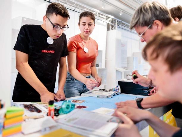 Jugendliche basteln gemeinsam an einem Tisch im hellen Museumsworkshop