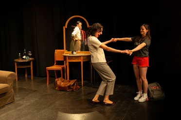 Theaterszene mit zwei Frauen beim Tanz, Spiegel und Requisiten auf dunkler Bühne